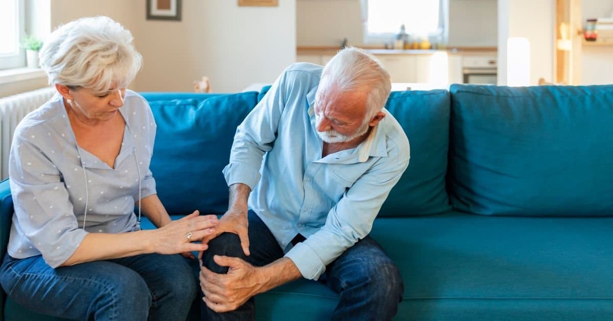 An older adult gently moving a joint affected by arthritis.